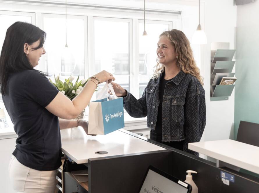 kvinde får udleveret Invisalign med guide til, hvad hun må og ikke må under behandlingen